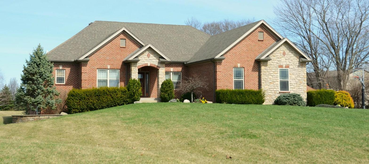 A brick home with a new dark shingle roof