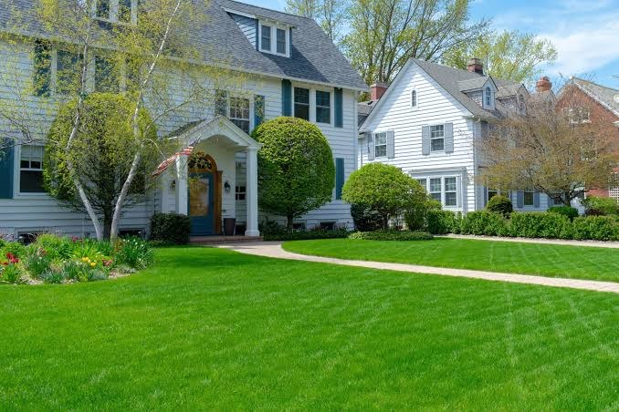 A curving front walkway through a green lawn to a white colonial house